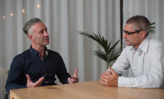 Two men (Mark Nesbitt and Thomas Lebor) in a meeting room, deep in conversation